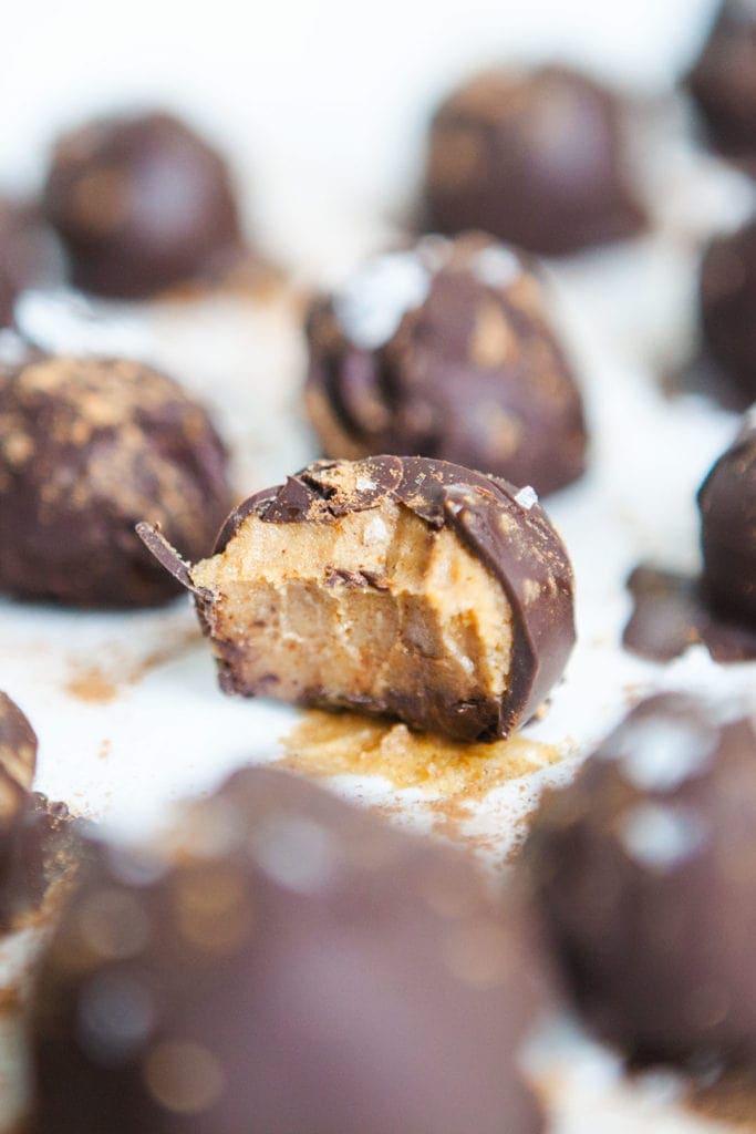 Vegan pumpkin chocolate truffles with bite taken out, from the side.