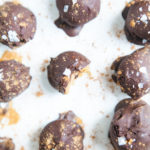 Vegan pumpkin chocolate truffles from above with bite taken out of one on white background.