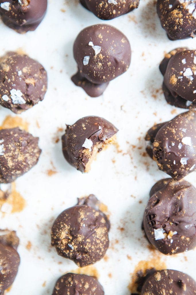 Vegan pumpkin chocolate truffles from above with bite taken out of one on white background.