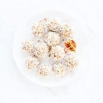 Pumpkin spice energy bites with one with a bite taken out on a white plate.