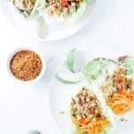 Chicken lettuce wraps with cauliflower rice on white plates with lime slices.
