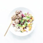 Butternut squash bowls with baked meatballs and tahini sauce in a white bowl.