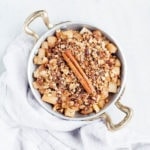 Healthy apple crisp in a small pan with a stick of cinnamon.