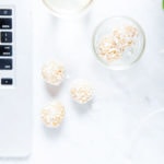 Lemon bliss balls with laptop and glass of lemon water.