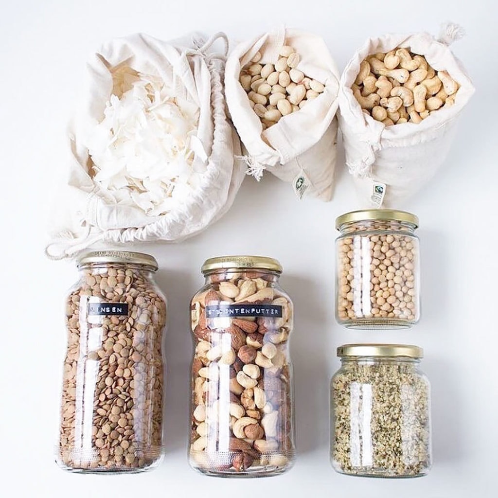 Bulk bin items in jars and cotton bags on a white background.