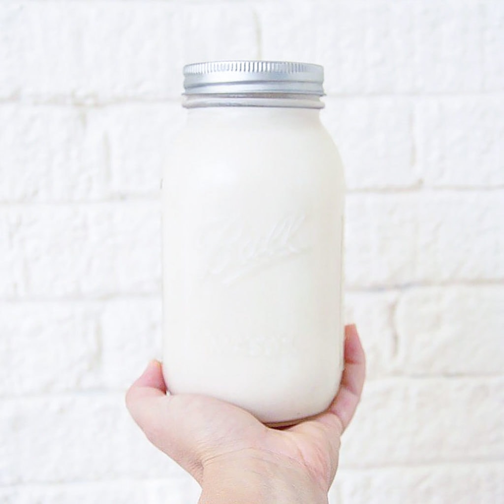Cashew yogurt in a mason jar being held by a hand.
