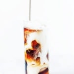 Coconut cold brew coffee with coconut milk in a tall glass with ice and a straw.