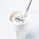 Tahini date shake in a tall white glass with a straw.