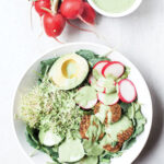Baked falafel on a salad with green tahini sauce.
