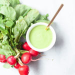 Green tahini sauce with a bunch of radishes.