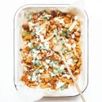 Sheet pan harissa chicken with sweet potatoes in a white casserole dish.
