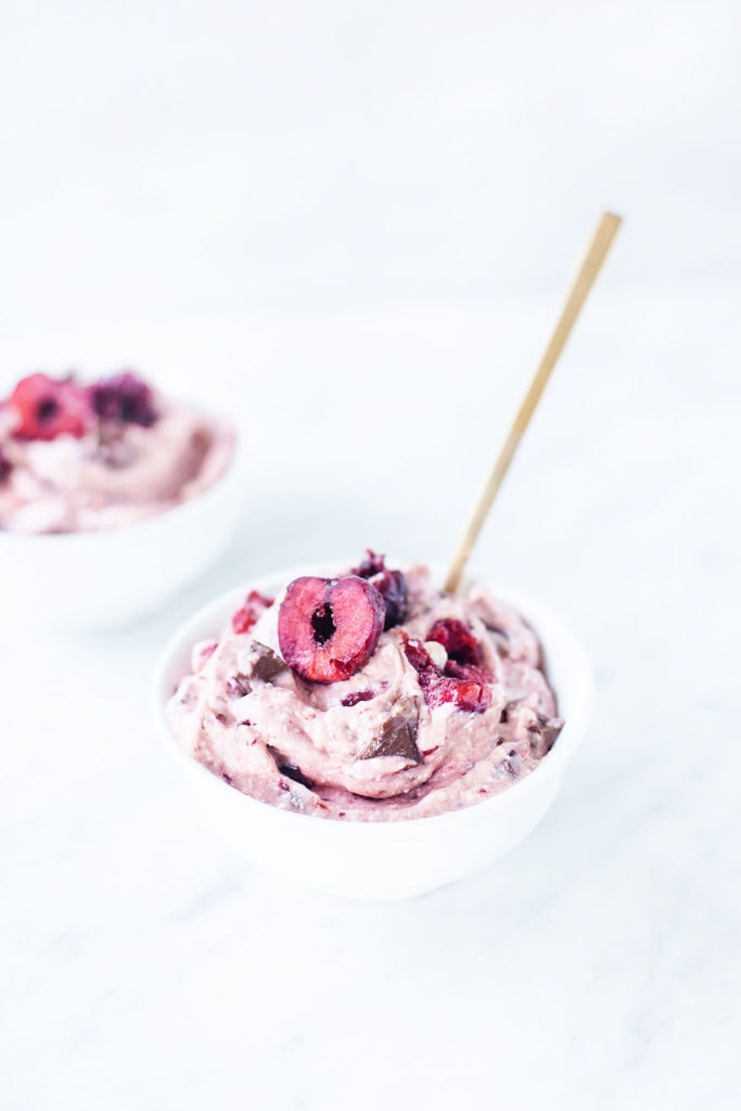 Cherry chocolate chip nice cream in a white bowl with a spoon.