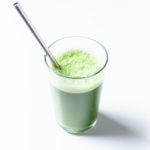 Glass of blender green juice with a metal straw.