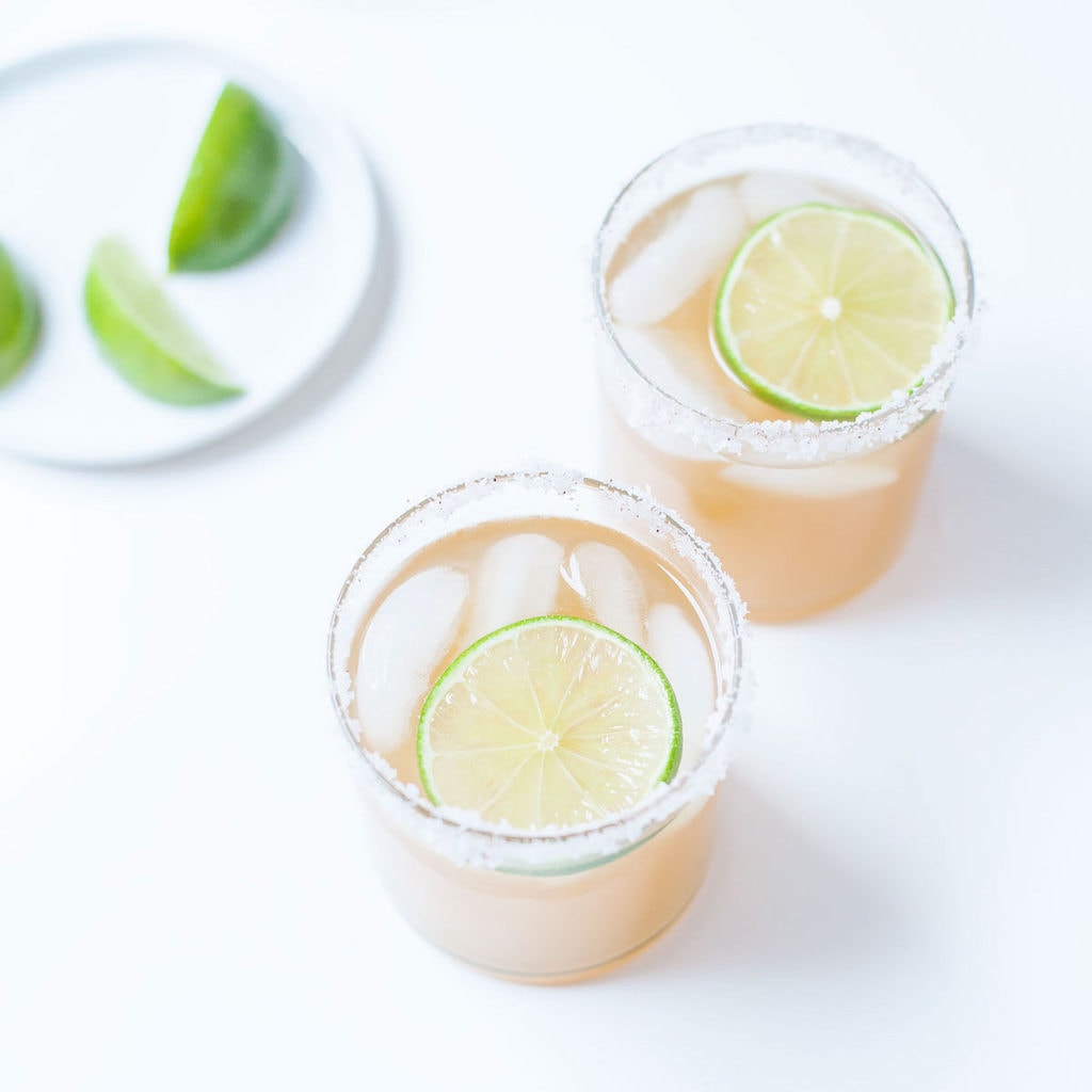 Kombucha margaritas in two cocktail glasses with lime slices.