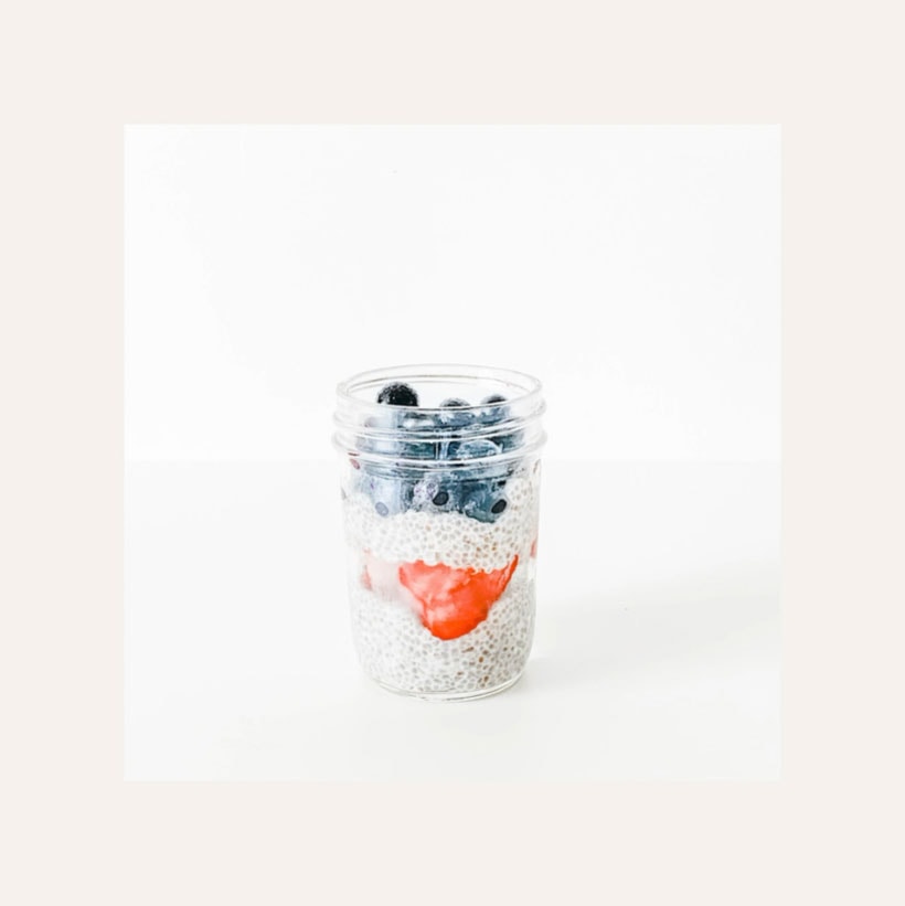 July 4th chia pudding in a jar with strawberries and blueberries.