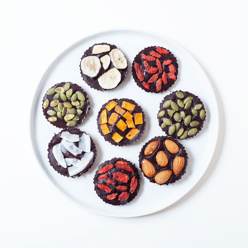 Homemade vegan chocolate with colorful toppings on a white plate.