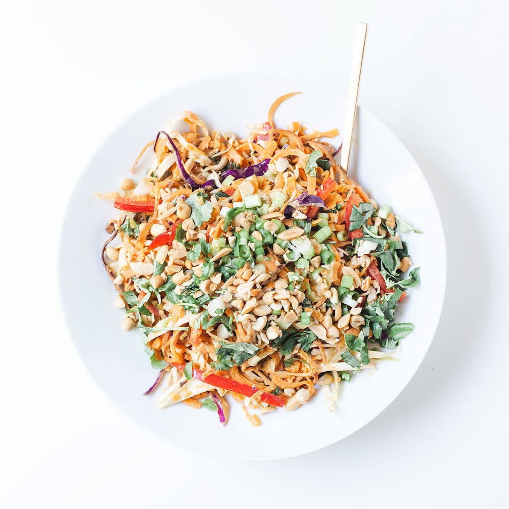 Sweet potato noodle bowls with coconut peanut sauce in a white bowl.