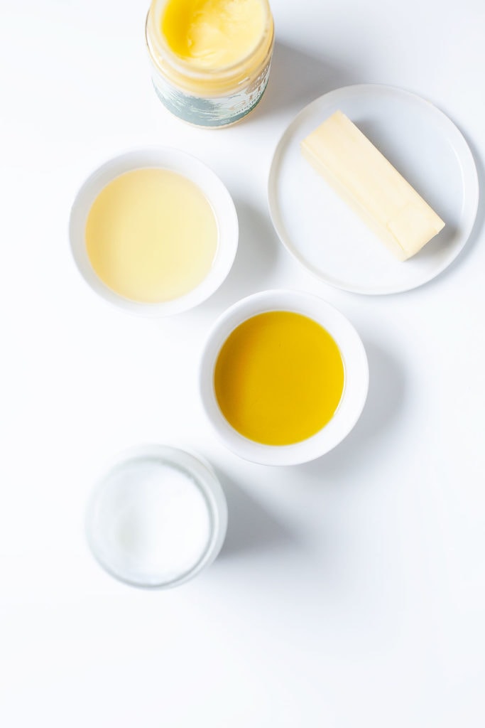 Cooking fats and oils in white containers on a white background.