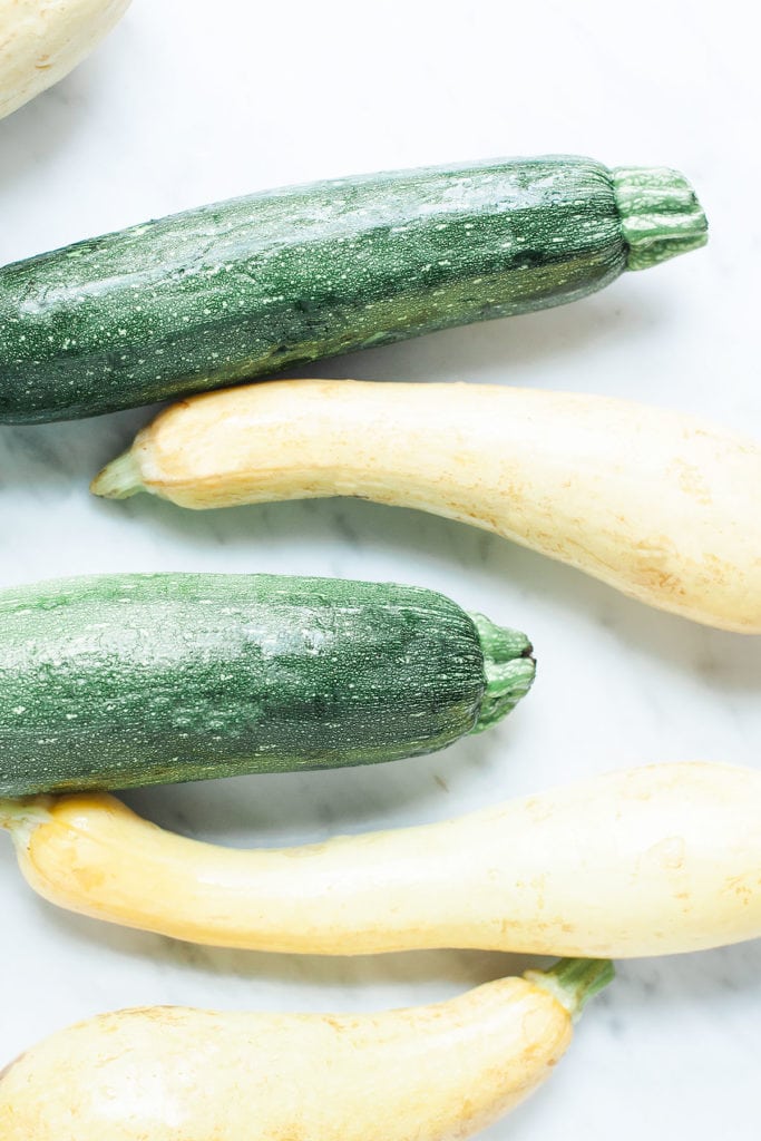 Zucchini and yellow summer squash on a white table.