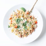 Healthy street corn salad in a white bowl on a white surface.