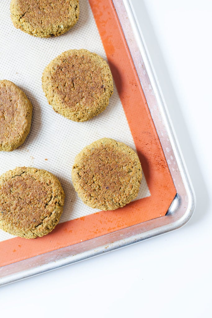 Peanut edamame burgers wrapped in lettuce on a baking sheet from above.