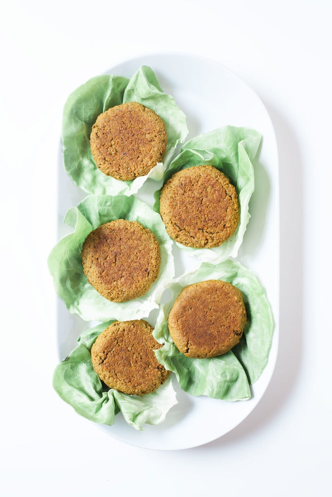Peanut edamame burgers wrapped in lettuce on a white platter from above.