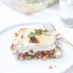 Gluten-free chicken pot "pie" on a white plate with cauliflower mash on top.