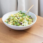 Miso maple sheet pan brussels sprouts and tofu in a white bowl on a wooden table.